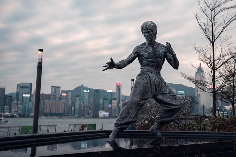 A statue of bruce lee in front of a city